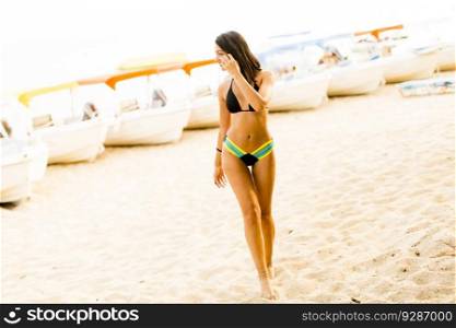 Young woman on the sandy beach with boats at summer