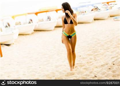 Young woman on the sandy beach with boats at summer