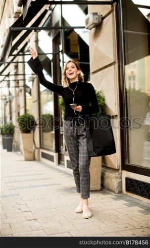 Young woman on the street with mobile phone and listening music