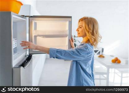 Young woman opened the fridge on the kitchen. Female person cooking breakfast at home in the morning, healthy nutrition and lifestyle