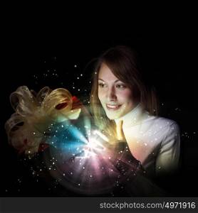 Young woman opening a gift box with shining and glittering lights around her