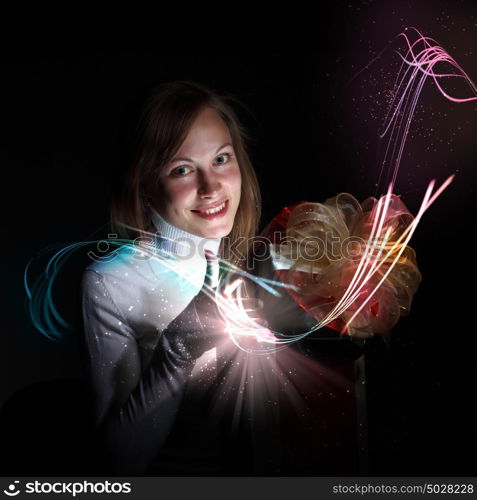 Young woman opening a gift box with shining and glittering lights around her