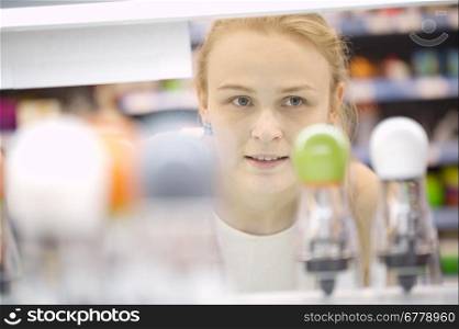 Young woman out shopping looking at merchandise in a store - view through products