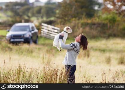 Young Woman Outdoors In Autumn Landscape Holding Dog