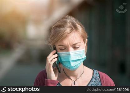 Young woman outdoors wearing a face mask and smartphone. Corona and flu season.
