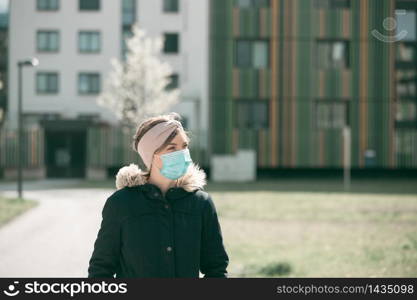 Young woman outdoors wearing a face mask. Corona and flu season.