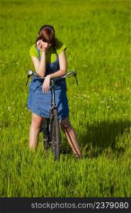 Young woman over a bike on a beautiful spring day and thinking on something