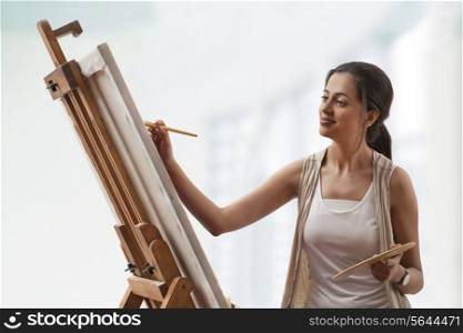 Young woman painting on canvas