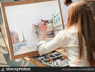 young woman painting outside, focus point on hand (selective)