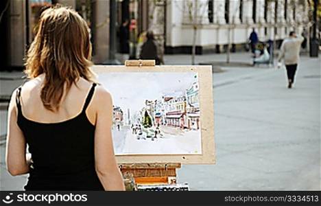 young woman painting outside, focus point on image