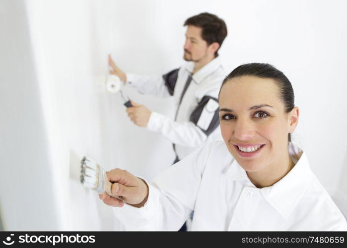 young woman painting wall in room