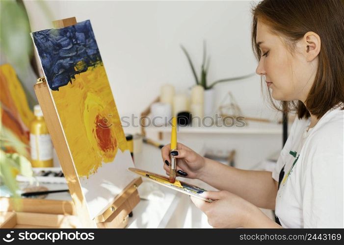 young woman painting with acrylics home
