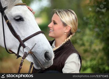 Young woman patting her horse