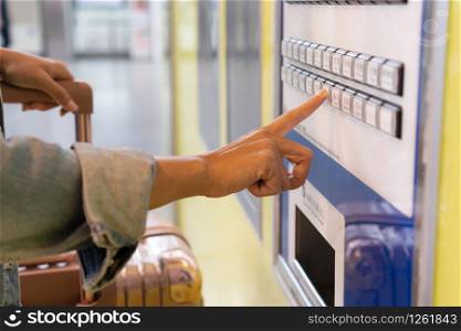 Young woman paying at ticket machine in a train station