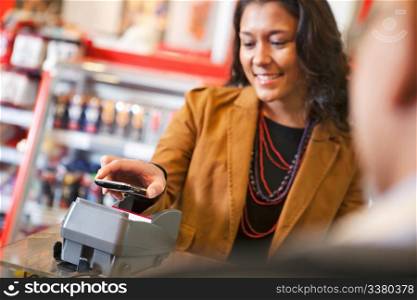 Young woman paying for purchase with cell phone
