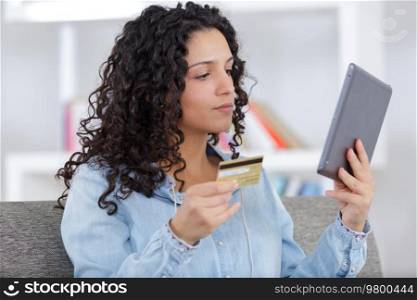 young woman paying with a credit card on the tablet