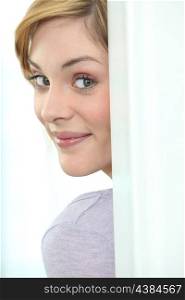 Young woman peeking round a door