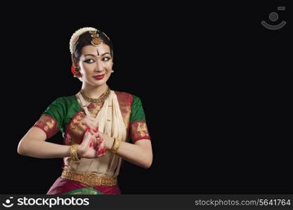 Young woman performing Bharatanatyam over black background