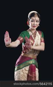 Young woman performing Bharatanatyam over black background