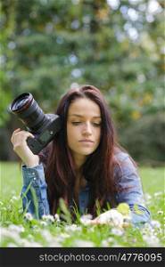 young woman photographer with camera lie down on grass