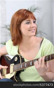 Young woman playing a guitar at home