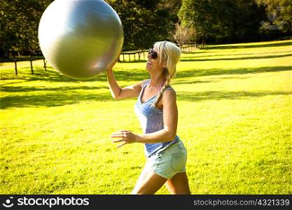 Young woman playing around with exercise ball in field