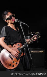 Young woman playing guitar during the concert