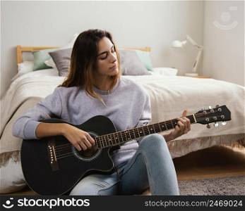 young woman playing guitar home