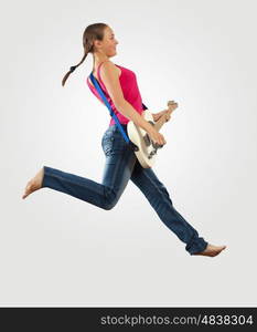 young woman playing on electro guitar and jumping