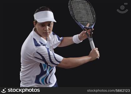 Young woman playing tennis over black background