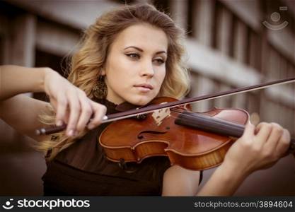 Young woman playing the violin at outdoors. Shallow depth of field.