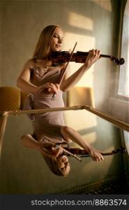 Young woman playing violin. Portrait with reflection in mirror. Female violinist recording online performance. Young woman playing violin, portrait with reflection in mirror