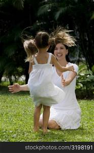 Young woman playing with her daughter in a park