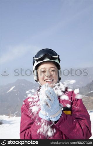 Young Woman Playing with Snow in Ski Resort