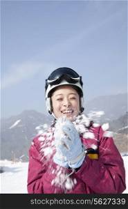 Young Woman Playing with Snow in Ski Resort