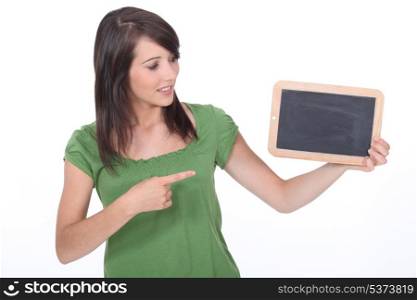 Young woman pointing at a blank blackboard