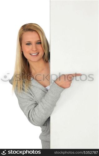 Young woman pointing at a board left blank for your message