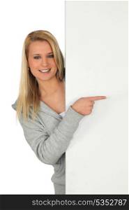 Young woman pointing at a board left blank for your message