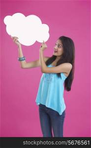 Young woman pointing at thought bubble over pink background