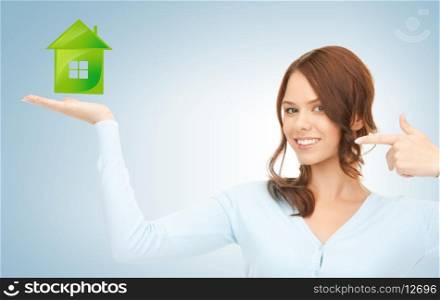 young woman pointing her finger at green eco house