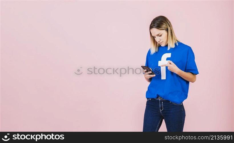 young woman pointing mobile phone pink background