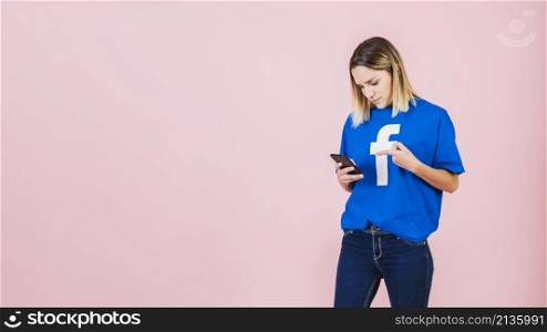 young woman pointing mobile phone pink background