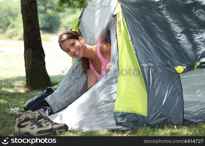 Young woman popping her head out of a tent