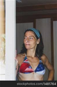 Young woman portrait leaning on a door side wearing swimsuit and a headband and looking away. MartaRodriguez.jpg