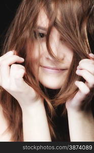 Young woman portrait teen smiling girl having fun pulling her long brown hair on black