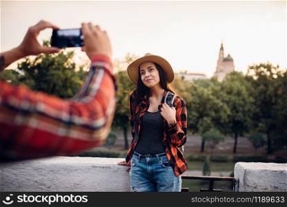 Young woman poses on excursion in tourist town. Summer hiking of love couple. Hike adventure of young man and woman. Young woman poses on excursion in tourist town