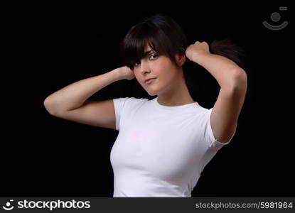 Young woman posing in black background holding her hair