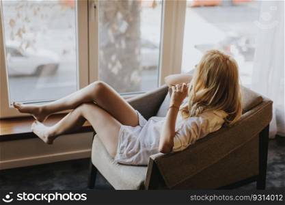 Young woman posing in lingerie by window in the room