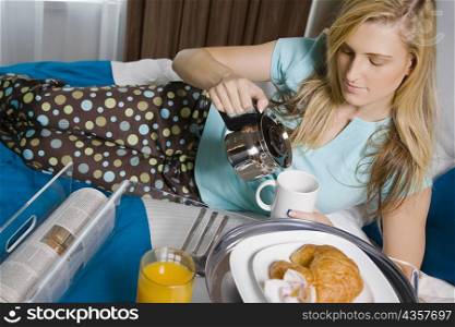 Young woman pouring tea into a tea cup