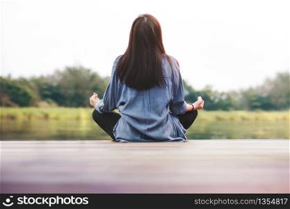 Young Woman Practices Yoga in Outdoor. Sitting in Lotus Position. Unplugged Life and Mental Health Concept. Sukhasana Posture and Meditating